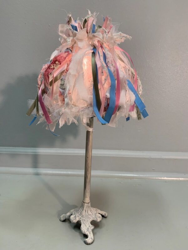 A lamp with ribbons on the top of it
