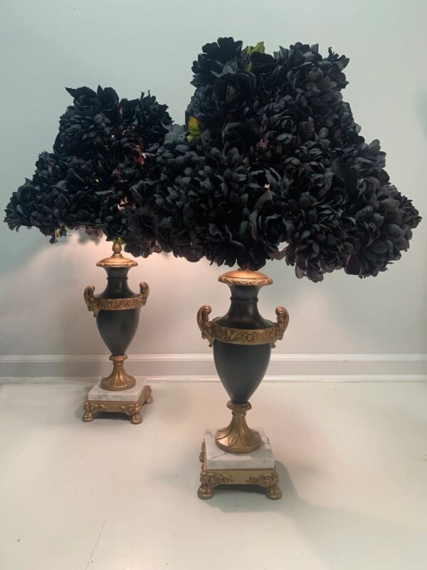 Two black lamps with a gold base and some trees